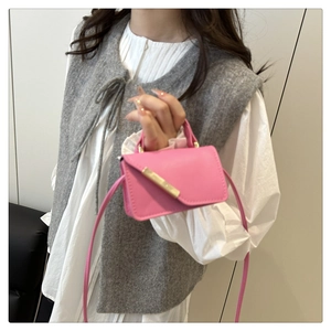 Mini rose pink crossbody bag with gold metal trim worn by model in casual style