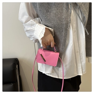Detailed view of mini pink crossbody bag with gold metal trim and leather strap on model