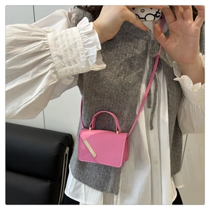 Détail d'un mini sac carré rose avec garniture en métal doré et bandoulière en cuir