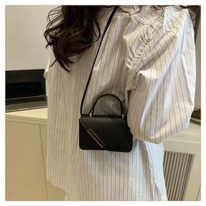 Détail d'un mini sac bandoulière noir mat avec un élégant accent de barre en métal doré