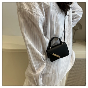 Détail du sac bandoulière en cuir noir avec boucle rectangulaire en métal doré