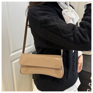 Glossy light brown PU leather baguette bag worn over the shoulder with a minimalist outfit