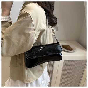 Gros plan d'un sac à bandoulière baguette en cuir verni noir au design minimaliste chic