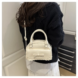 Close-up of cream bowling bag featuring delicate lace edges and a sweet bow detail