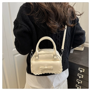Detail showing the cream mini bowling bag with a ribbon bow and delicate lace trim