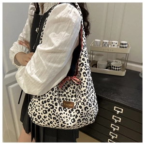 Detail of leopard print canvas tote bag featuring a leather fashion label and red drawstring