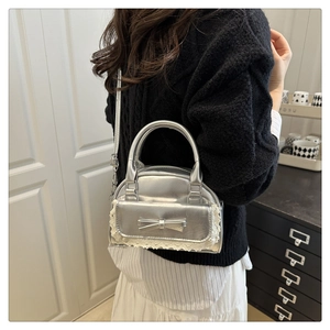 Close-up of silver bowling bag with bow decoration and delicate white lace trim details