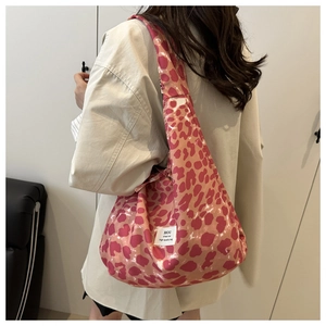 Close-up of pink leopard print tote bag worn with a beige blazer for a retro look