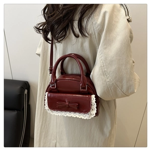 Close-up of wine red glossy bowling bag with white lace trim and bow detail