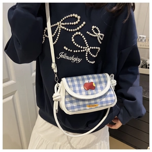Detail of blue and white checkered mini saddle bag with apple embroidery and knot strap