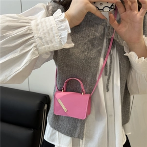 Pink crossbody bag with gold metal trim and slim shoulder strap worn by a model