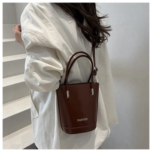 Detailed view of a brown leather bucket bag featuring white FASHION text and silver hardware