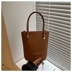 Close-up of brown leather handbag with silver metal handle connector and fashion logo