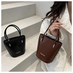 Détail de sacs seaux tendance avec poignées métalliques en noir et marron classique