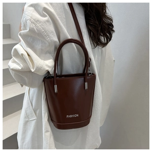 Detail of a dark brown leather bucket bag with silver hardware and fashion lettering