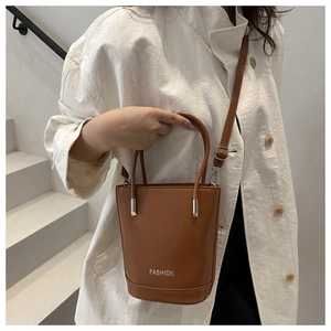 Close-up of brown leather bucket bag with FASHION logo and silver hardware detail