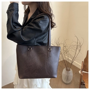 Detail showing deep brown leather tote bag with vintage texture worn on the shoulder