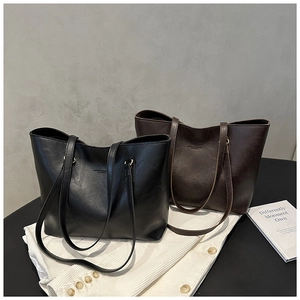 Detail of minimalist leather tote bags in black and brown with reinforced shoulder straps