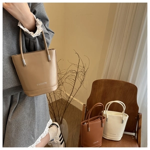 Detailed shot of khaki, dark brown and cream bucket bags with subtle fashion branding