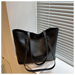 Detail of minimalist black tote bag with leather texture and white logo for commute