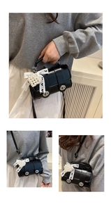 Detail der schwarzen zylindrischen Handtasche mit Perlenherz und Spitzen-Schleife