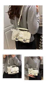 Detail der cremeweißen Lederhandtasche mit silbernen Drehverschlüssen und Perlen-Schleifen-Anhänger