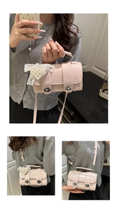 Detail der rosafarbenen Perlglanz-Mini-Tasche mit Herz-Perlenanhänger und Silberknöpfen
