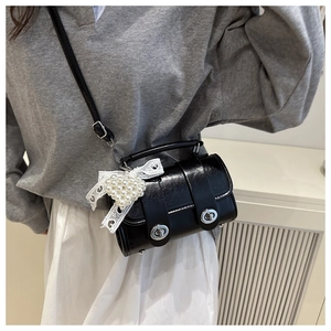 Detalle de bolso negro de hombro con colgante de corazón de encaje y perlas