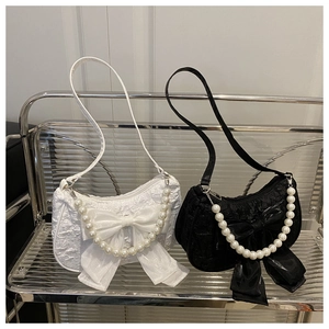 Side-by-side view of black and white crescent handbags with bows and pearl handles