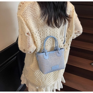 Detail shot of a blue and white woven bucket bag with Fashion leather patch on stairs