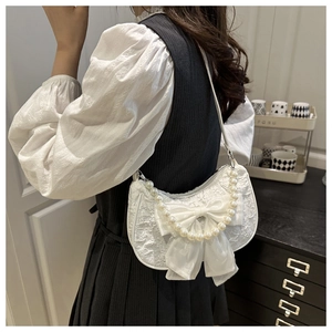 Detail of white lace handbag with large chiffon bow and premium pearl handle decoration