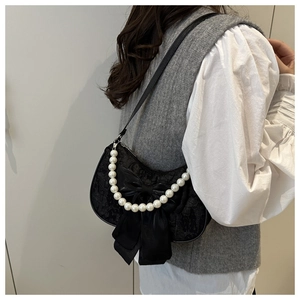 Close-up of black lace underarm bag with large satin bow and pearl handle detail