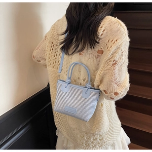 Detail view of light blue woven bucket bag showing its texture and leather patch