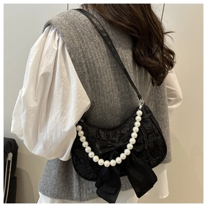 Detail of black bow shoulder bag with pearl chain strap and textured jacquard fabric