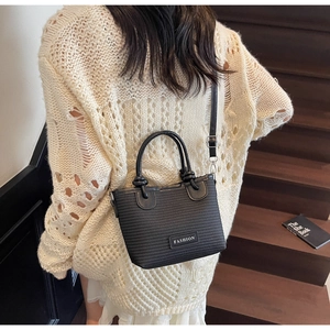 Detail of black woven tote bag with FASHION label and adjustable strap on a shoulder