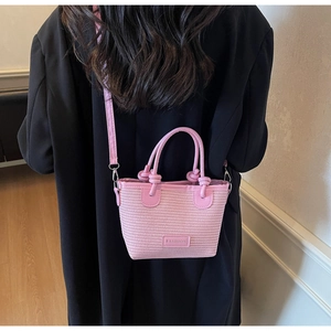 Detail of pink woven bucket bag with FASHION label and adjustable PU shoulder strap