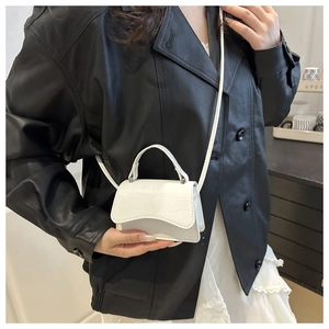 Detail of white crocodile texture mini bag with scalloped flap and slender strap