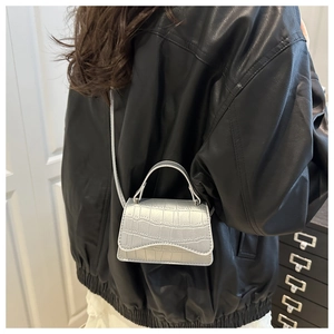 Silver crocodile textured small crossbody bag shown in a side-view lifestyle pose