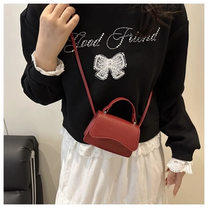 Vue détaillée d'un mini sac à bandoulière rouge motif crocodile porté par un mannequin