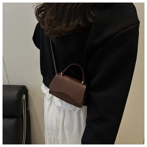 Close-up of a dark brown mini bag with leather texture and wavy edge design