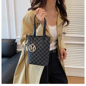 Close-up of retro monogram bucket bag with gold M pendant and black leather strap