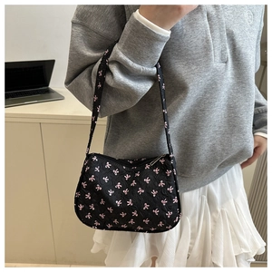 Detail of black baguette bag with pink bow pattern and bubble textured fabric