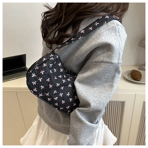 Quilted black hobo bag with pink bow print shown on model in a casual cafe setting