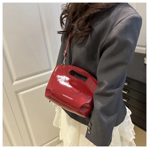 Detail of red patent leather bucket bag with cutout handle and silver hardware