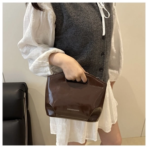 Macro detail of dark brown glossy leather handbag with silver Fashion & Bags engraving