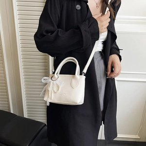 White mini crossbody bag with pearl lace bow charm and premium lychee leather texture