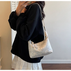 Détail du motif jacquard géométrique et de la bandoulière en cuir du sac beige