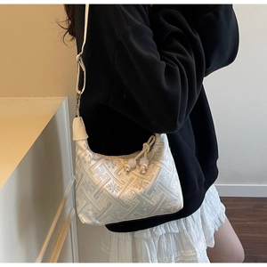 Detail der weißen Jacquard-Schultertasche mit geometrischem Muster und Perlenanhänger
