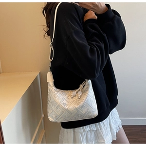 Detail of white jacquard shoulder bag featuring traditional patterns and pearl pendants