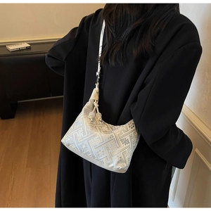 Détail du sac à bandoulière argenté brodé avec motifs floraux sur un manteau noir
